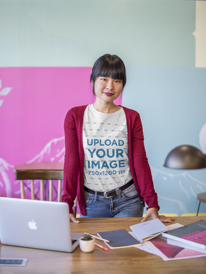 Asian Woman Leaning Over a Desk Wearing a T-Shirt Mockup at the Office