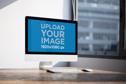 Angled Shot of an iMac Mockup Standing on a Wooden Desk