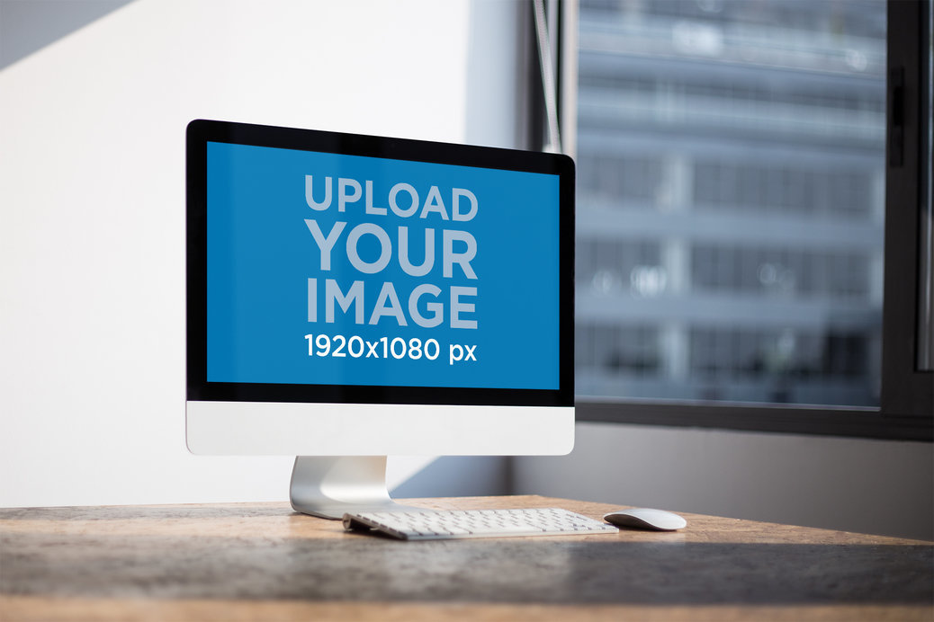 Angled Shot of an iMac Mockup Standing on a Wooden Desk