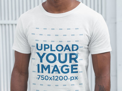 Closeup of a Man Wearing a T-Shirt Mockup Against a White Metal Door
