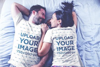 Back and Front Sides of T-Shirts Mockup Being Worn by a Happy Couple Resting on Bed