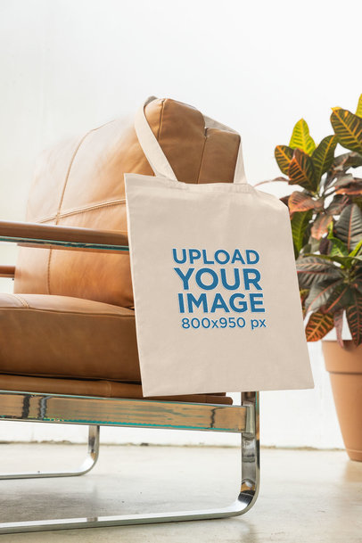 Mockup of an Embroidered Tote Bag Hanging From an Armchair
