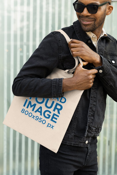 Mockup of a Man with Sunglasses Carrying an Embroidered Tote Bag