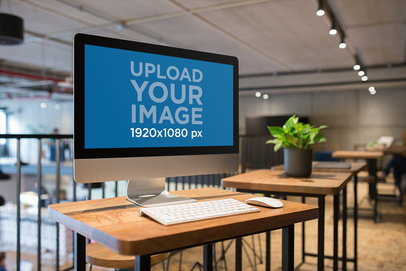 Angled Shot of an iMac Mockup at a Workstation Wooden Desk
