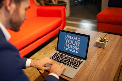 Man Using a MacBook Mockup on a Wooden Coffee Table