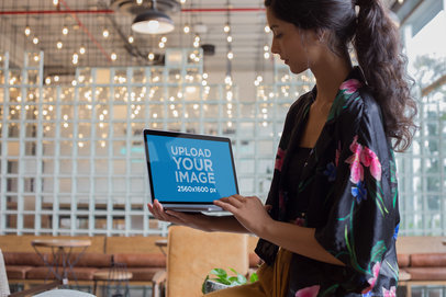 Woman Using a MacBook Mockup while Standing at a Startup