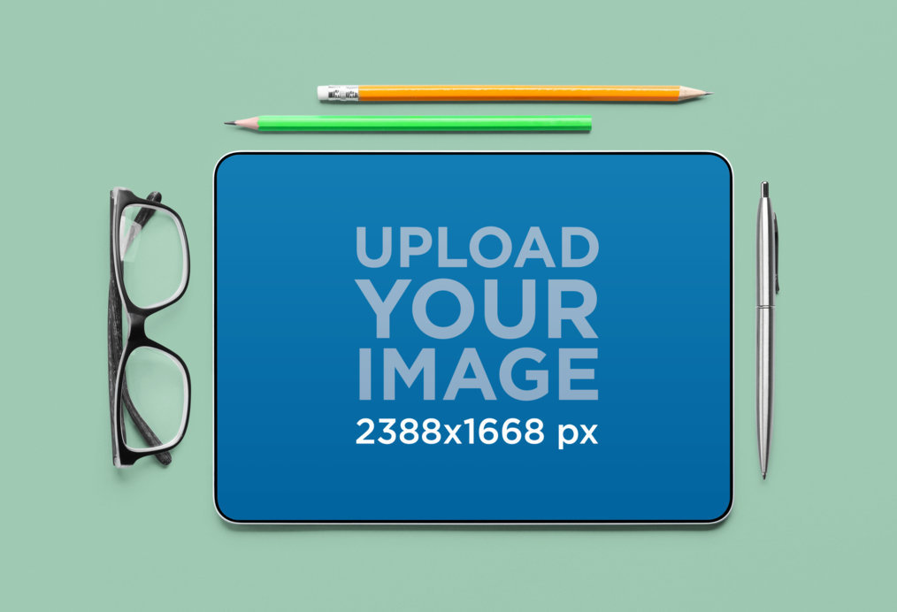 Mockup of an iPad Placed on a Customizable Surface Surrounded by Pens and a Pair of Glasses