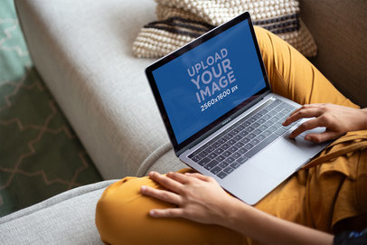 Woman Working with a MacBook Mockup Sitting on a Sofa