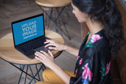 Woman Working on a MacBook Mockup Over a Coffee Table