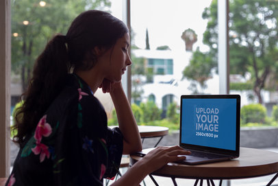 Woman Working with a MacBook Mockup on a Small Round Wooden Table