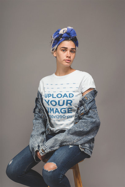 Freckled Woman with Denim Clothing Wearing a T-Shirt Mockup Sitting on a Stool