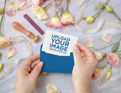 Mockup of Woman Holding a Wedding Invitation Featuring Flowers