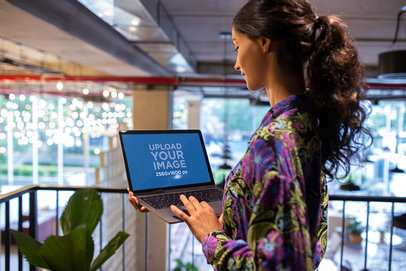 Woman Working with MacBook Mockup Standing Near a Plant