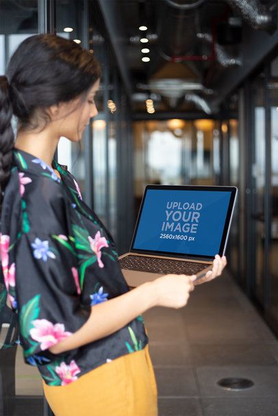 Standing Woman Working with MacBook Mockup at a Hallway
