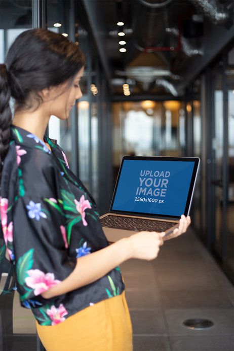 Standing Woman Working with MacBook Mockup at a Hallway