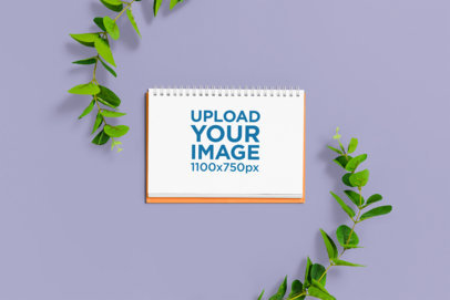 Mockup of a Notebook Lying on a Customizable Background Surrounded by Branches