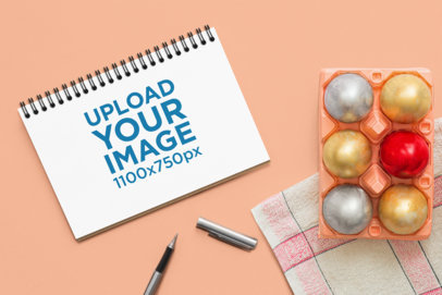 Notebook Mockup Featuring Painted Eggs and a Pen