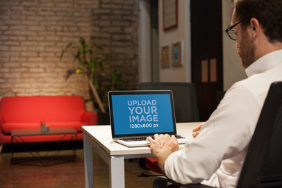 Mockup of a Man Working with a MacBook on a White Table