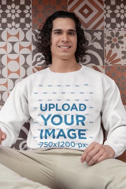 Gildan Sweatshirt Mockup of a Man with Curly Hair Sitting by a Tiled Wall
