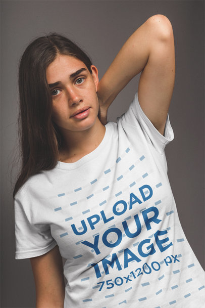Mockup of a Young White Woman Wearing a Tshirt in a Grey Room