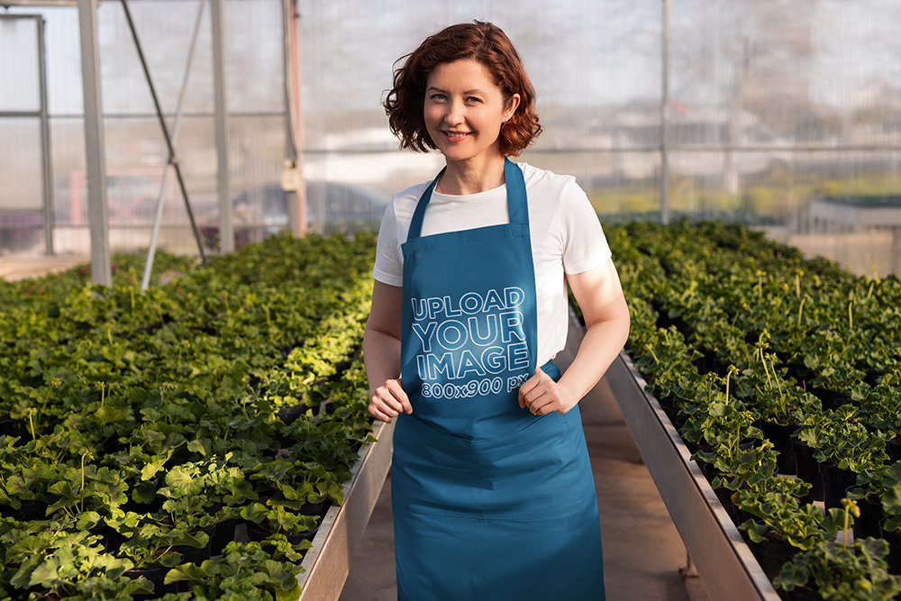 Apron Mockup Featuring a Smiling Woman in a Greenhouse