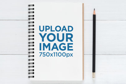 Mockup of a Spiral Notebook Placed Next to a Pencil