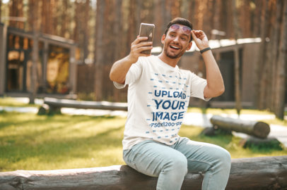 Round-Neck T-Shirt Mockup Featuring a Smiling Man Taking a Selfie in the Park