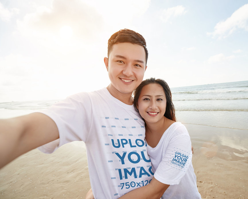 T-Shirt Mockup Featuring a Happy Couple Taking a Selfie by the Beach