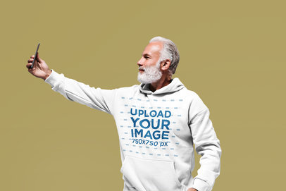 Pullover Hoodie Mockup Featuring a Senior Man Taking a Selfie