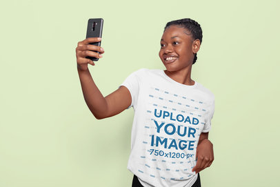 T-Shirt Mockup of a Smiling Woman Taking a Selfie in a Studio