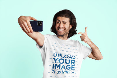 T-Shirt Mockup Featuring a Smiling Man Taking a Selfie in a Studio