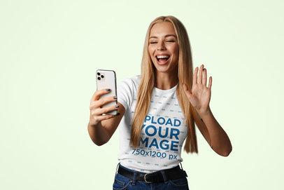 Round-Neck T-Shirt Mockup Featuring a Cheerful Woman Taking a Selfie in a Studio