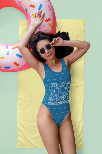 Mockup of a Woman in a Sublimated Swimsuit Lying on a Towel