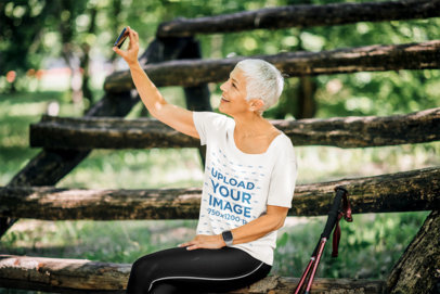 T-Shirt Mockup Featuring an Elderly Woman Taking a Selfie