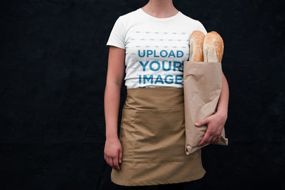 T-Shirt Mockup of a Woman Holding Baguettes and Wearing an Apron