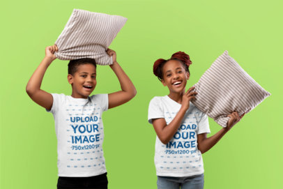 T-Shirt Mockup of a Happy Girl and a Boy Holding Pillows in a Studio