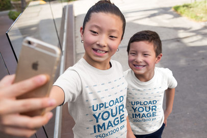 T-Shirt Mockup Featuring Happy Asian Kids Taking a Selfie on the Street