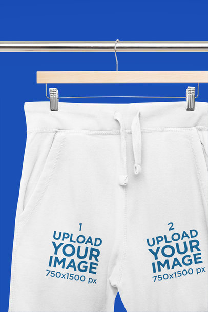 Mockup of a Pair of Sweatpants Placed on a Wooden Hanger With a Customizable Surface m33405