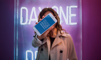 Mockup of a Woman Holding an iPhone 7 Plus Against her Face while Near a Neon Sign a21279