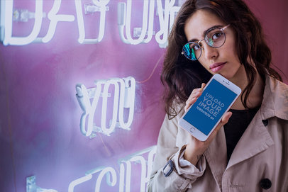 Mockup of a Pretty Woman Holding a Rose Gold iPhone 7 Plus by a Neon Sign a21281