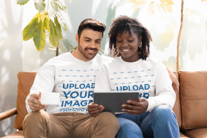Gildan Sweatshirt Mockup Featuring a Happy Man and Woman Using a Tablet