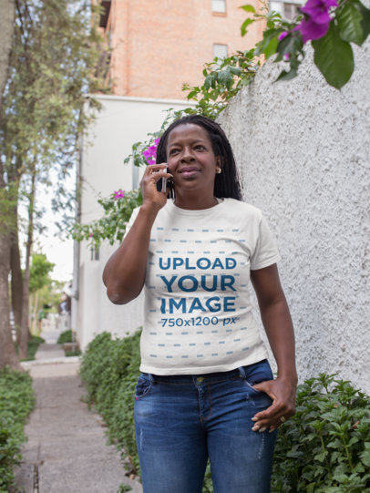 Portrait T-Shirt Mockup of a Senior Woman Talking on her Phone while on the Street