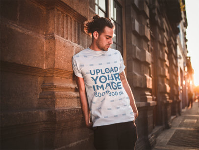 Mockup of a Man Wearing a Sublimated T-Shirt while Leaning Against a Historical Building