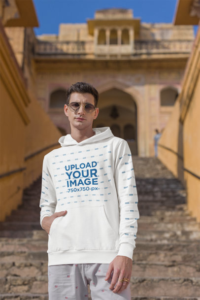 Gildan Pullover Hoodie Mockup Featuring a Man Posing Against a Historical Monument