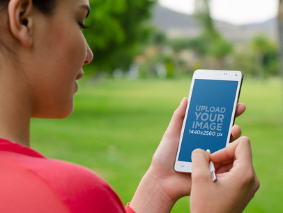 Woman Using a Samsung Galaxy Note 4 Outdoors at the Park | Mockup Generator