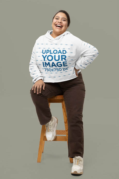 Bella Canvas Cropped Hoodie Mockup Featuring a Cheerful Woman Sitting on a Stool