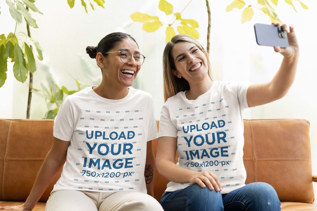 Bella Canvas Tee Mockup of Two Happy Women Taking a Selfie While Sitting on a Couch