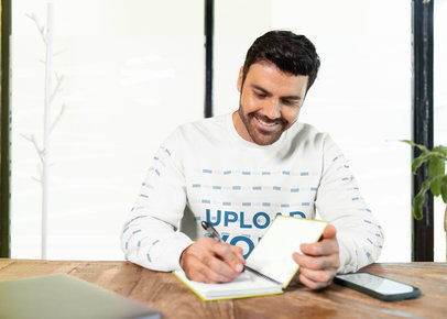 Gildan Sweatshirt Mockup Featuring a Happy Bearded Man Writing in a Notebook