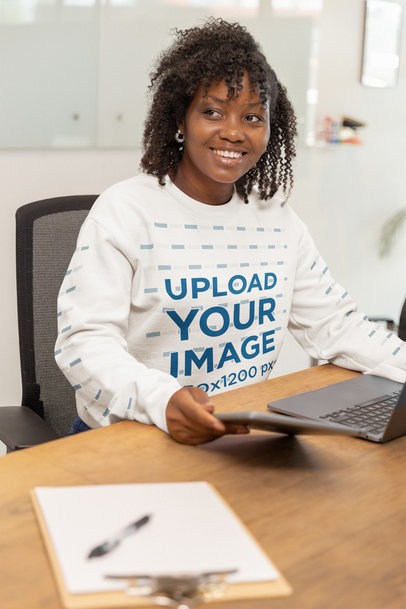 Gildan Sweatshirt Mockup of a Smiling Woman Sitting on a Wooden Desk