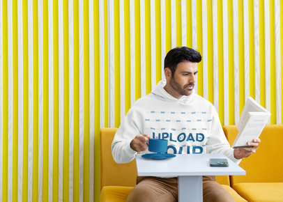 Gildan Pullover Hoodie Mockup of a Bearded Man Drinking Coffee and Reading a Book